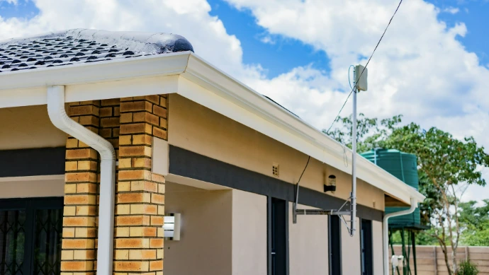 A brick and stucco house exterior with a white gutter and antenna